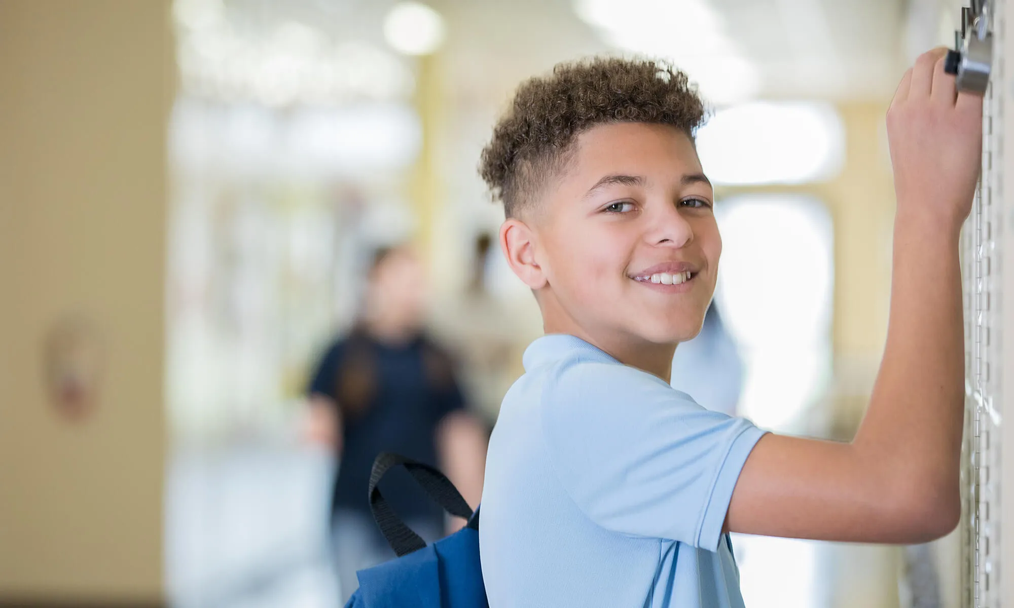 A male middle school student opening his locker