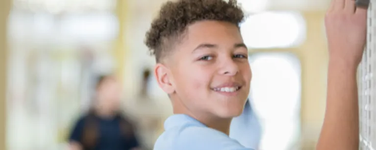 student looking over while opening locker