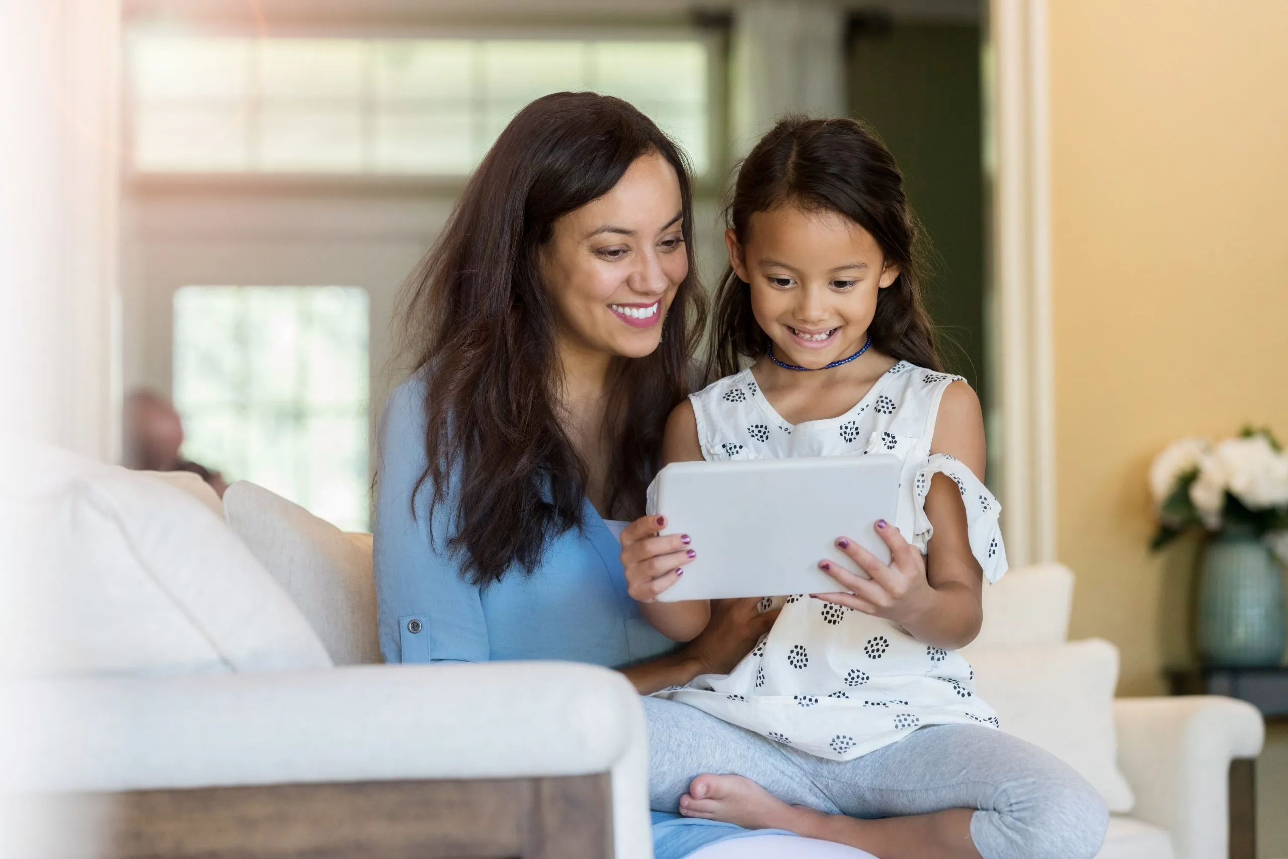 Little girl and her mom read a story on digital tablet