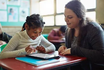 teacher helping student on tablet