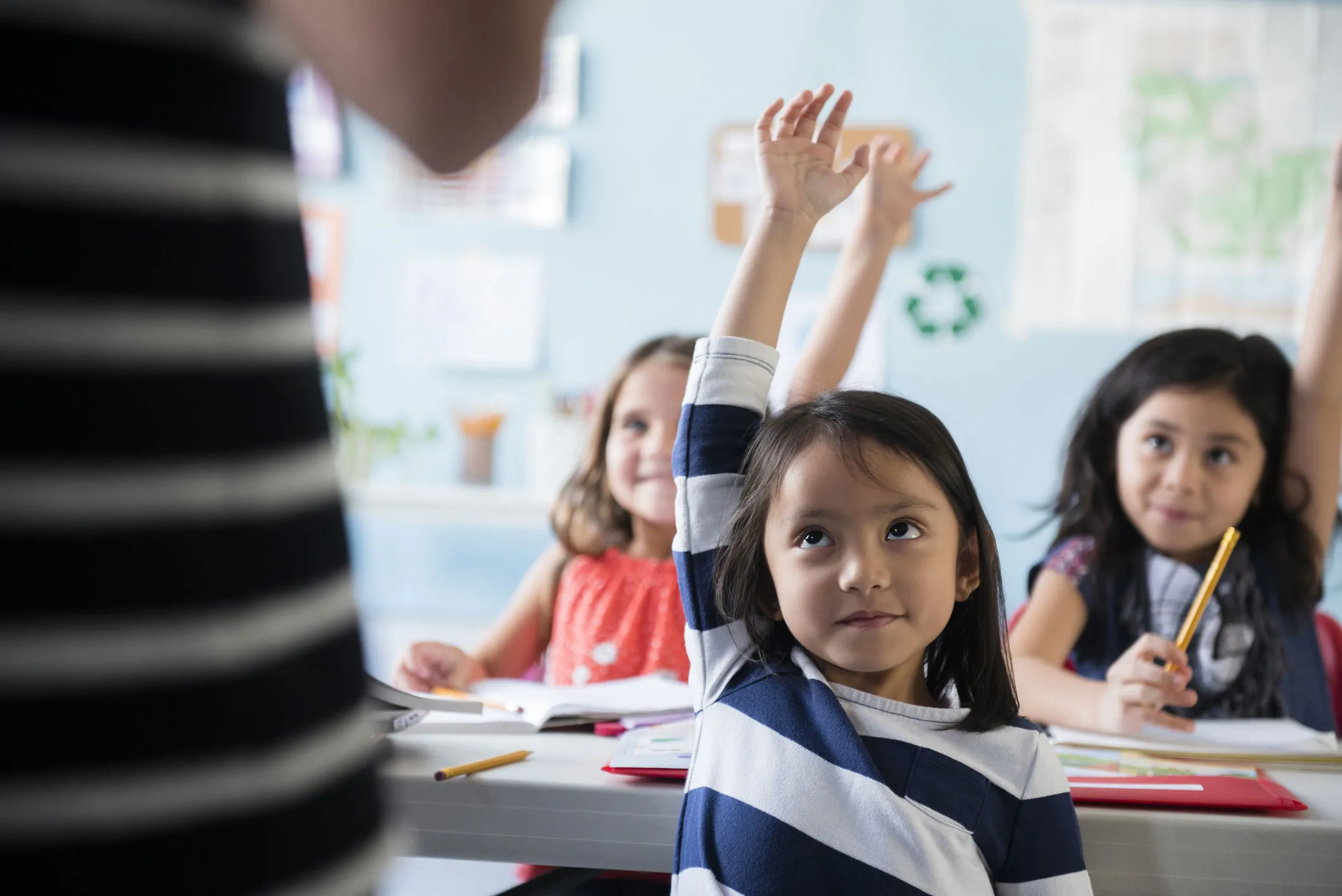 young students raising their hands