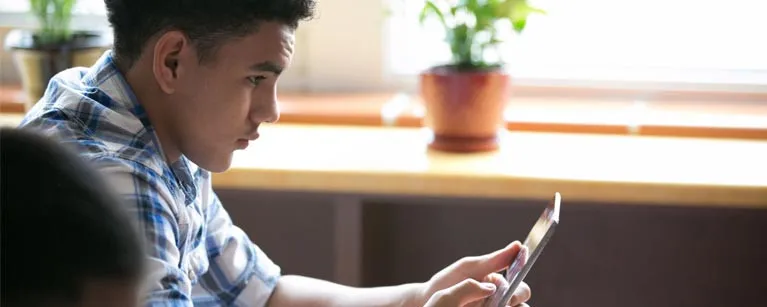 kid reading on tablet by the window