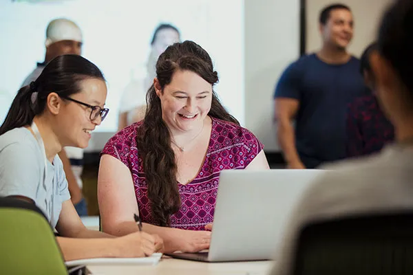 teachers surrounding laptop smiling