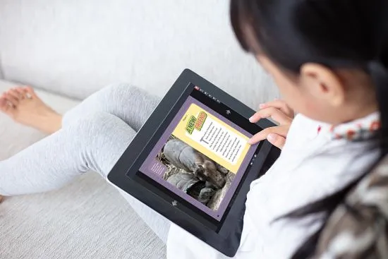 young girl on tablet while sitting on couch