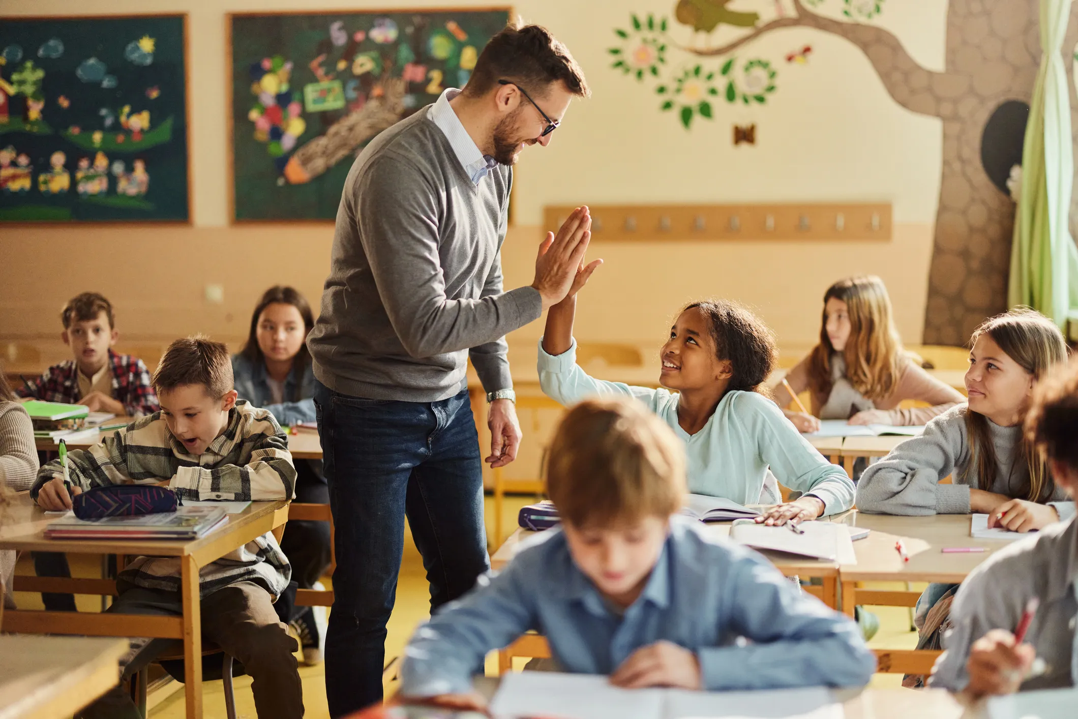 teacher gives student high five in classroom