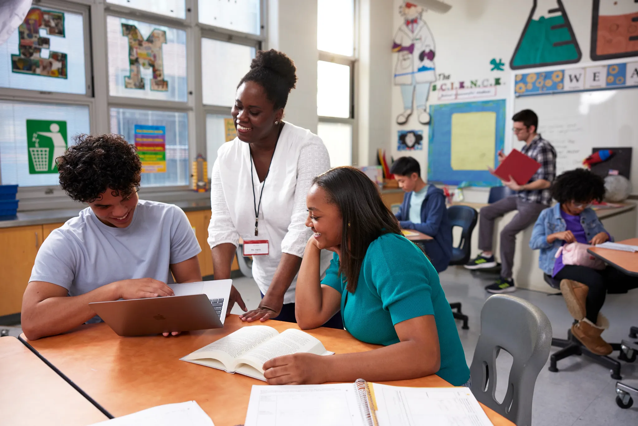 teacher helping two students at their desk