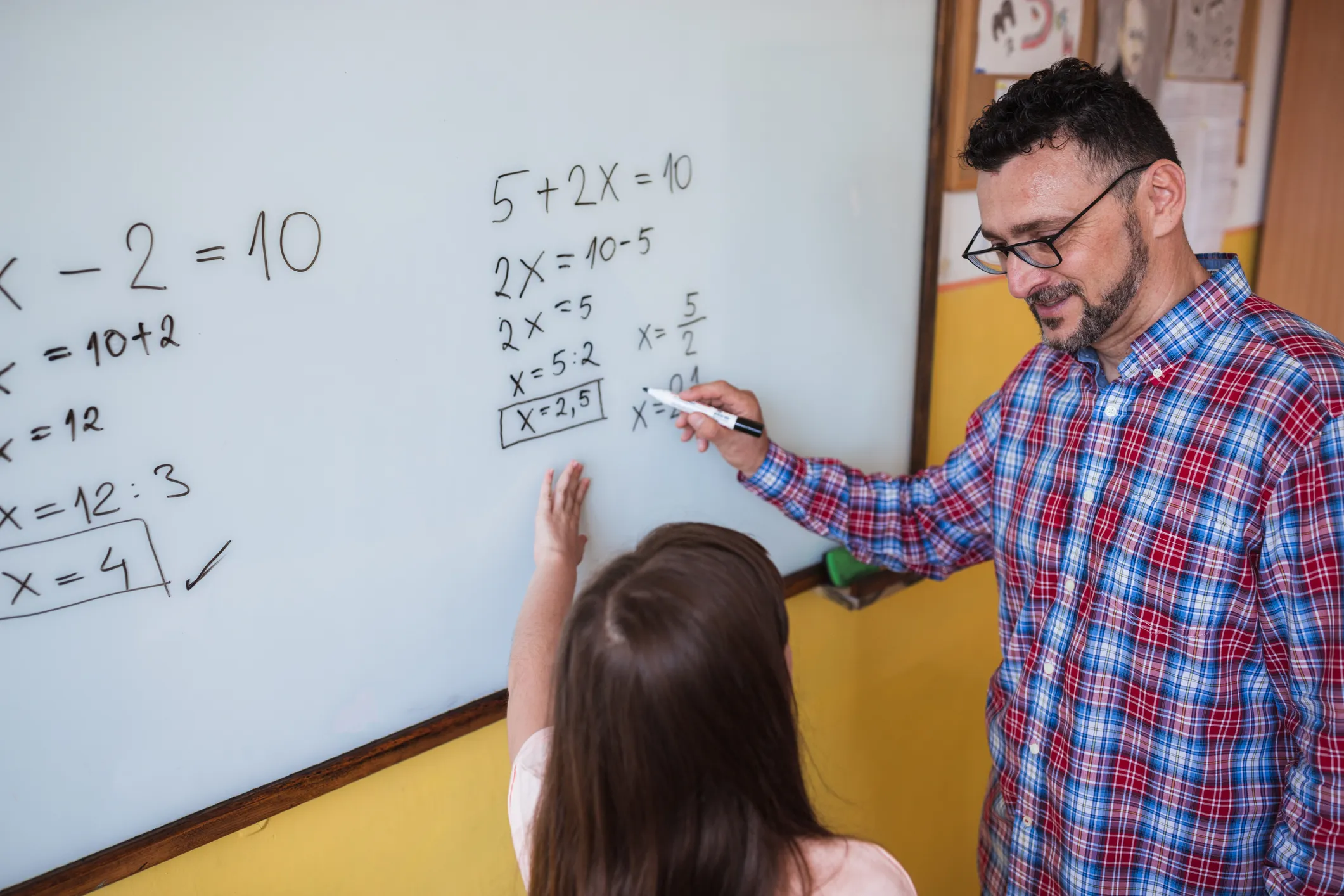 A math teacher helping a student at a whitepoard