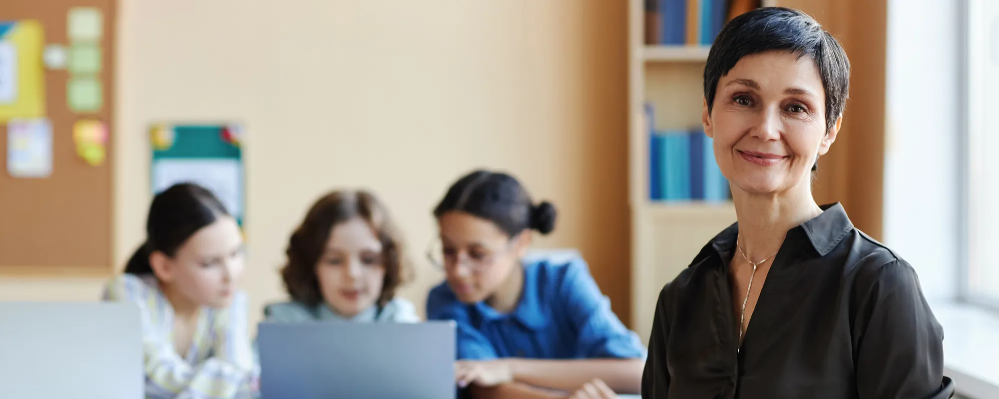 teacher smiling with students doing groupwork in the background