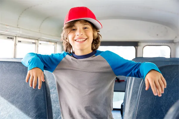 A young student on a bus wearing a cap