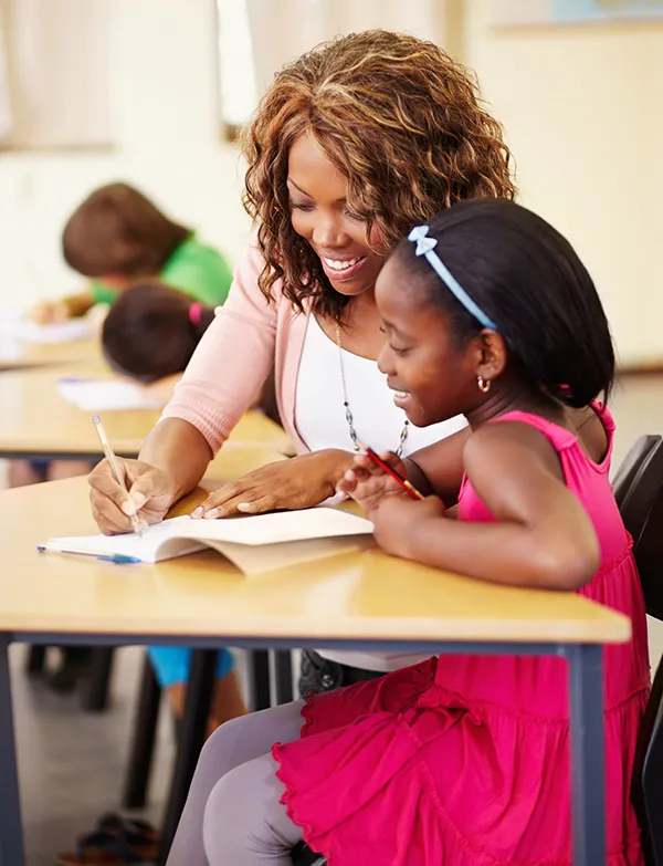 A teacher helping an elementary school student read a book